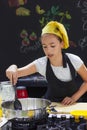 Young girl in a chef`s hat cooks in a large saucepan in a black Royalty Free Stock Photo