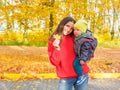 Young girl with a child on the background of fallen yellow foliage in the park