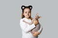 Young girl child painting kitten face holding cat pet on grey background Royalty Free Stock Photo