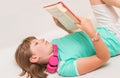 Young girl child is reading book on the sofa at home Royalty Free Stock Photo