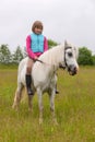 Young girl child sitting astride a white horse Royalty Free Stock Photo