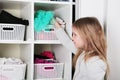 Young girl choosing dress in wardrobe at home. The wardrobe which put in order. All things are folded neatly. Many boxes. Everythi Royalty Free Stock Photo