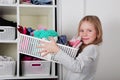 Young girl choosing dress in wardrobe at home. The wardrobe which put in order. All things are folded neatly. Many boxes. Everythi Royalty Free Stock Photo