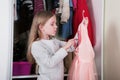 Young girl choosing dress in wardrobe at home. The wardrobe which put in order. All things are folded neatly. Many boxes. Everythi Royalty Free Stock Photo