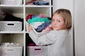 Young girl choosing dress in wardrobe at home. The wardrobe which put in order. All things are folded neatly. Many boxes. Everythi Royalty Free Stock Photo