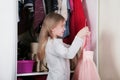 Young girl choosing dress in wardrobe at home. The wardrobe which put in order. All things are folded neatly. Many boxes. Everythi Royalty Free Stock Photo