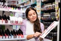 Girl choosing nail polish from color samples in makeup store