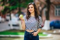 Young girl on the city street with smartphone and eating big apple Royalty Free Stock Photo