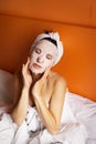 Young girl with clean skin with a mask on her face, lying in bed, resting after a shower, relaxing at home. Close-up Royalty Free Stock Photo