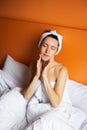 Young girl with clean skin with a towel on her head lying in bed, resting after a shower, relaxing at home Royalty Free Stock Photo