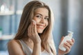 Young girl cleaning her face with tonic, removing makeup in front of mirror in bathroom Royalty Free Stock Photo