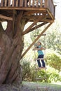 Young Girl Climbing Rope Ladder To Treehouse
