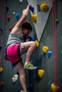 Young girl climbing up on practice wall in indoor rock gym Royalty Free Stock Photo