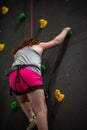 Young girl climbing up on practice wall in indoor rock gym Royalty Free Stock Photo