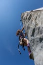 Young girl climbing on vertical wall with ropes outdoors warm summer day.