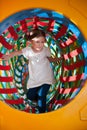 Young girl climbs through netted tunnel in soft play centre