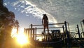 Young girl climibing playground equipment as the sun is setting