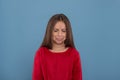 A young girl with closed eyes and a pouty lip upsets with something against a blue background with copy space in the studio