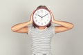 Girl closing face by round clock