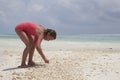 Young girl collecting sea shells on a beach, close up