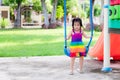 Young girl in colorful dress was playing on blue swing and was tired and sweat wet her hair.