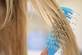 Young girl combing her wet blond hair with a blue comb. Royalty Free Stock Photo