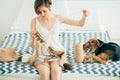 Young craftwoman in nightdress knitting sweater on bed. Cute cur dog besides. Home, freelance, handmade mood concept Royalty Free Stock Photo