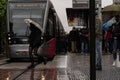 Young girl crosses fast in front of the tram on a rainy day.