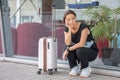 A young girl is squatting with a suitcase near the window. Perhaps she missed her plane or train, is very worried, or is waiting Royalty Free Stock Photo