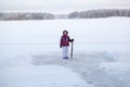 Young girl with crowbar in hand standing near cleared ice on lake for making ice-hole Royalty Free Stock Photo