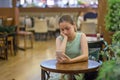 Young girl is crying along in a cafe closing her face with her hand. Teenager broke up with boyfriend