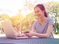 Young girl with cup of coffee and a phone in her hands working on a laptop at the table in the park. The concept of shopping Royalty Free Stock Photo