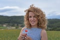 Young girl with curly blond hair, with a red flower in her hands and smiling Royalty Free Stock Photo