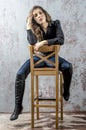 Young girl with curly hair in a black shirt, jeans and high boots cowboy western style