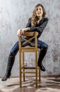 Young girl with curly hair in a black shirt, jeans and high boots cowboy western style