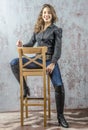 Young girl with curly hair in a black shirt, jeans and high boots cowboy western style