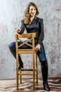 Young girl with curly hair in a black shirt, jeans and high boots cowboy western style Royalty Free Stock Photo