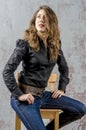 Young girl with curly hair in a black shirt, jeans and high boots cowboy western style