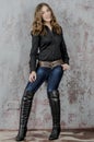 Young girl with curly hair in a black shirt, jeans and high boots cowboy western style