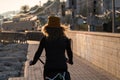 Young girl with curly hair fluttering in the wind riding a bicycle at sunset on the promenade road Royalty Free Stock Photo