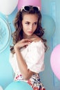 Young girl with dark curly hair and tender makeup, posing with colorful air balloons Royalty Free Stock Photo