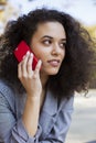 Young girl with dark curly hair using phone in a city park. Royalty Free Stock Photo