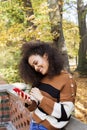 Young girl with dark curly hair using phone in a city park. Royalty Free Stock Photo