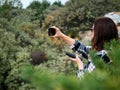 A young girl with dark hair, wearing glasses, takes photos of nature on her smartphone. The smartphone is charged from the power