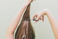 A young girl decided to cut her hair. In the hands of holding a bunch of hair and scissors. Long brown hair