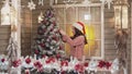 Young girl decorates Christmas tree by red balls at house porch in slomo