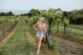 Young girl in denim shorts and sleeveless shirt posing in the vineyard on a summer day Royalty Free Stock Photo