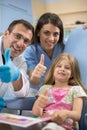 Young girl with dentist and his assistant show thumb up and smile Royalty Free Stock Photo