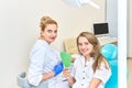 Young girl at the dentist`s appointment. woman sits in chair at the dentist and holds mirror in her hands