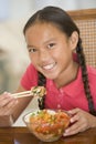 Young girl in dining room eating chinese food Royalty Free Stock Photo